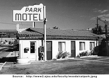 A motel building with a sign near a road